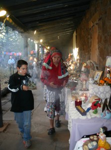 Juan Carlos Ortiz carries the traditional copal incense while Diego Chavez Petzey, Tz’ utujil Mayan elder, blesses the nearly two dozen altars in the courtyard of the Museum of Northern Arizona during the 2012 Celebraciones de la Gente.  The event, presented by the museum and Flagstaff Nuestras Raíces, is celebrating its 10th anniversary. Mariachi youth performances, ballet folklorico dancers, demonstrations on making ofrendas / altars, sugar skulls and papel picado; talks  and vendors located throughout the museum will be part  of the celebration this year. En la Portada: Juan Carlos Ortiz lleva el tradicional incienso de copal mientras Diego Chávez Petzey, anciano Tz ‘utujil Maya, bendice las casi dos docenas de altares en el patio del Museo del Norte de Arizona durante los Celebraciones de la Gente de 2012.  El evento, presentado por el museo y Flagstaff Nuestras Raíces, está celebrando su 10 º aniversario. Actuaciones de mariachis juveniles, bailarines de Ballet Folklórico, demostraciones sobre cómo hacer ofrendas/altares, calaveras de azúcar y papel picado, charlas y vendedores ubicados en todo el museo serán parte de la celebración este año. Photos / Fotos: Frank X. Moraga / AmigosNAZ 