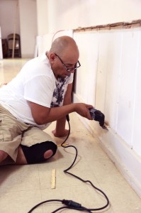 Armando Gonzalez trims up the baseboard before priming can begin. For decades, the basement at Our Lady of Guadalupe Church in Flagstaff has served as a community meeting place for celebrations, for mourning and other uses. And for years, the basement has been in dire need of an update. So when Father Patrick Mowrer put out a call for someone to start the renovation project, he didn’t have to wait long for work to begin on the community’s new cultural center. Photo / foto: Star Hunter / AmigosNAZ 