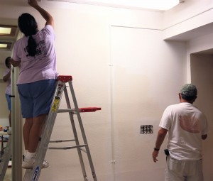 Loretta, a la izquierda, y Lupe Velasco aplican la primera capa de pintura en una pared del sótano. Foto: Frank X. Moraga / AmigosNAZ